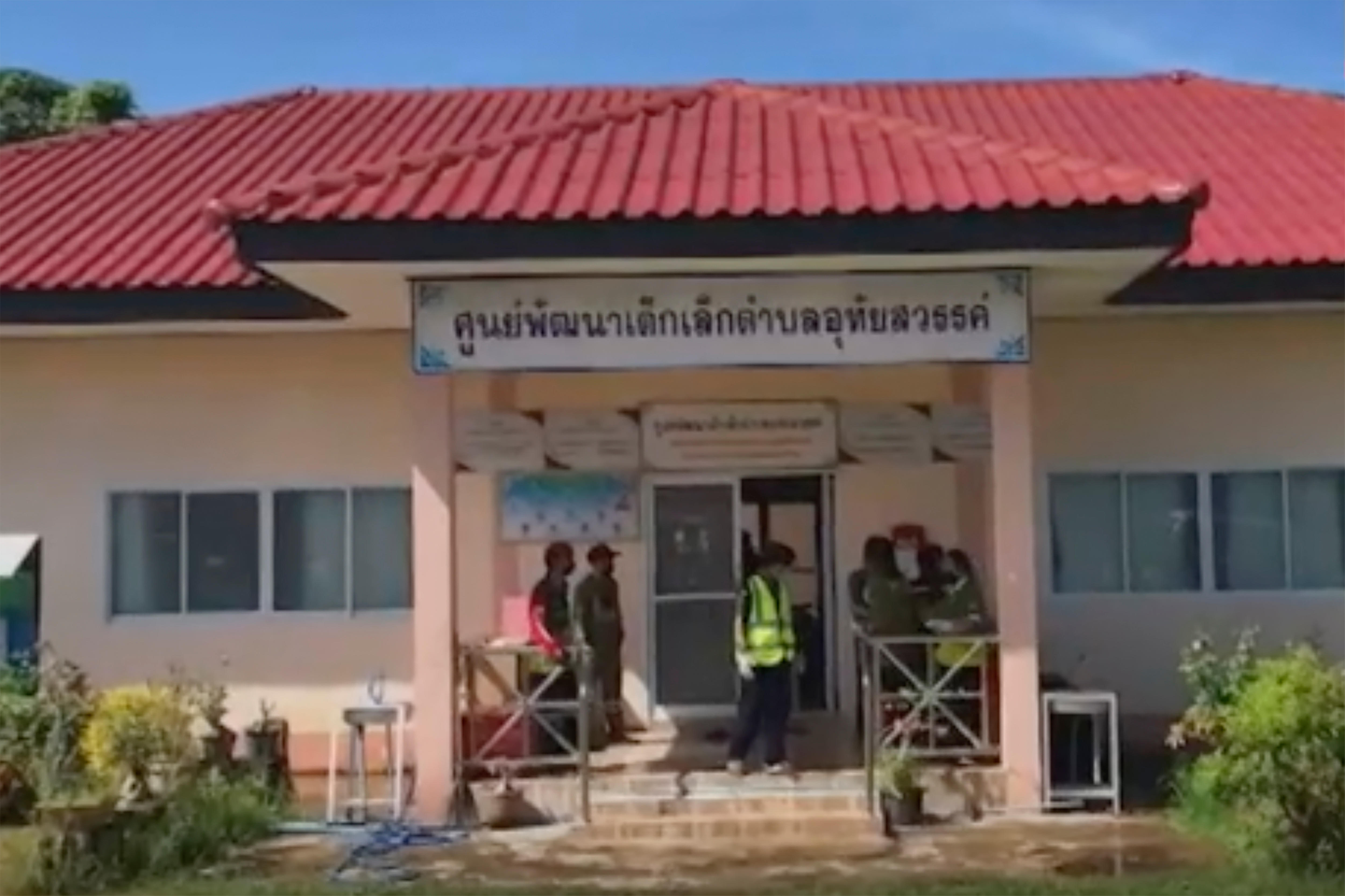 一个中心的正面是奶油色的墙壁和红色的屋顶，上面有泰语写在入口门口。“ class=